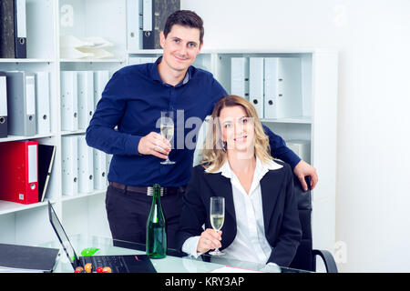 Giovane imprenditore e imprenditrice celebrando insieme in ufficio Foto Stock