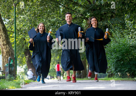 Istruzione, graduazione persone concetto - gruppo di felice gli studenti internazionali in mortaio e schede di corso di laurea gli abiti con diplomi Foto Stock