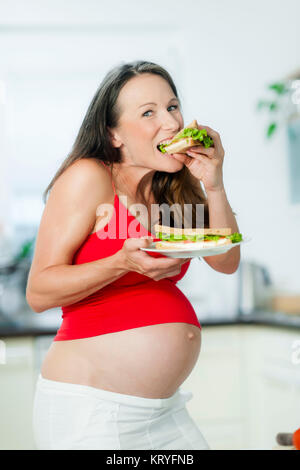 Schwangere Frau isst ein panino - donna incinta mangia un sandwich Foto Stock