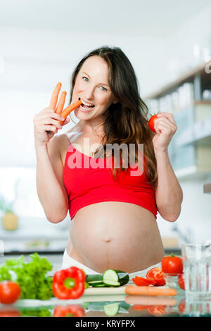 Schwangere Frau mit Gemüse beim Kochen - donna incinta con verdure Foto Stock