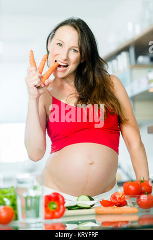 Schwangere Frau mit Gemüse beim Kochen in der Küche - donna incinta con verdure in cucina Foto Stock