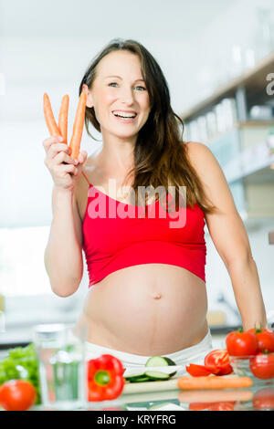 Schwangere Frau mit Gemüse beim Kochen in der Küche - donna incinta con verdure in cucina Foto Stock