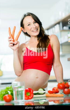 Schwangere Frau mit Gemüse beim Kochen in der Küche - donna incinta con verdure in cucina Foto Stock