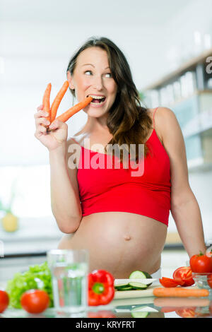 Schwangere Frau mit Gemüse beim Kochen in der Küche - donna incinta con verdure in cucina Foto Stock