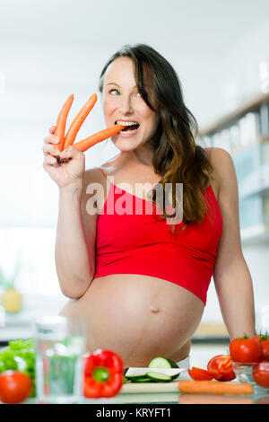 Schwangere Frau mit Gemüse beim Kochen in der Küche - donna incinta con verdure in cucina Foto Stock