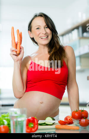 Schwangere Frau mit Gemüse beim Kochen in der Küche - donna incinta con verdure in cucina Foto Stock