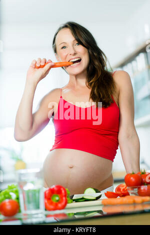 Schwangere Frau mit Gemüse beim Kochen in der Küche - donna incinta con verdure in cucina Foto Stock