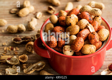 ciotola in ceramica rossa con diverse arachidi Foto Stock
