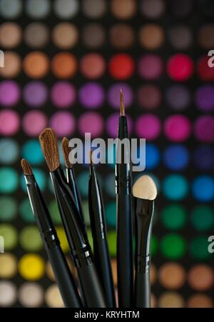 Cosmetici spazzole su un colorato costituiscono lo sfondo della tavolozza Foto Stock