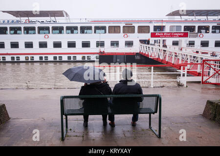 L'Europa, Germania, Colonia, in un giorno di pioggia una coppia di anziani seduti su una panchina sulle rive del fiume Reno, luce di allagamento. Europa, Deutschland, Koe Foto Stock