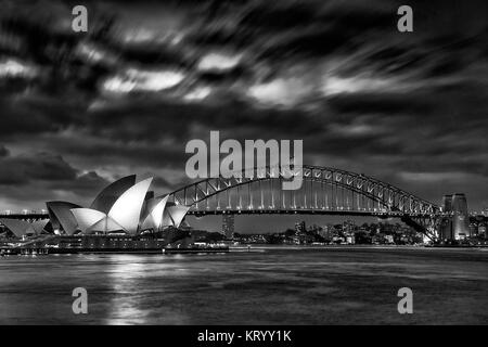 Sydney, Australia, 18 marzo 2017: famosa Sydney Opera House e Harbour Bridge al tramonto. Nuvole sfocata e luci dei punti di riferimento riflettono in blur Foto Stock