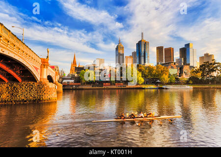 Golden la luce solare e la mattina ora su città di Melbourne CBD landmark alti torri sul lungomare di fiume Yarra e Princes ponte con exerci sfocata Foto Stock