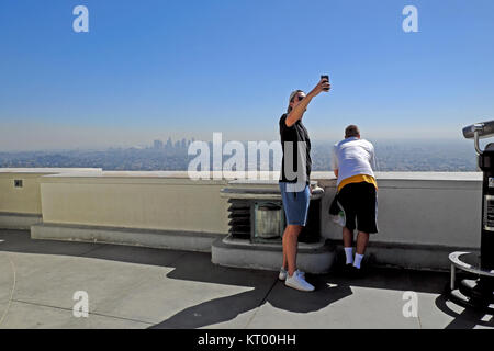 Un giovane uomo prendendo un selfie con la Downtown sfondo dall Osservatorio Griffith tetto al Griffith Park di Los Angeles, California USA KATHY DEWITT Foto Stock