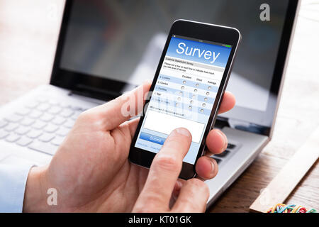 Imprenditore riempiendo il modulo del sondaggio sul telefono cellulare Foto Stock