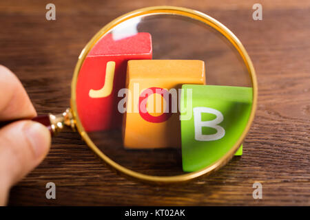 Persona che tiene la lente di ingrandimento sopra la parola Job Foto Stock