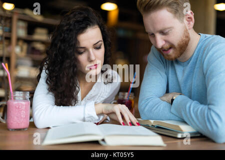 I giovani studenti di trascorrere del tempo in un coffee shop libri di lettura