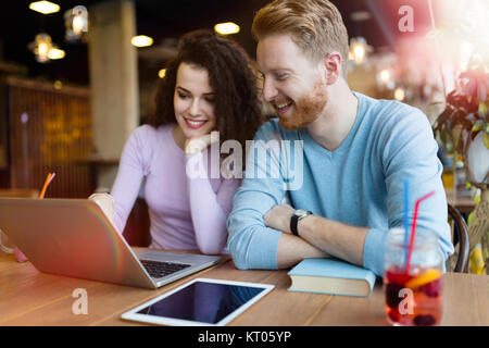 Coppia felice di trascorrere del tempo presso la caffetteria lavorando sul computer portatile Foto Stock