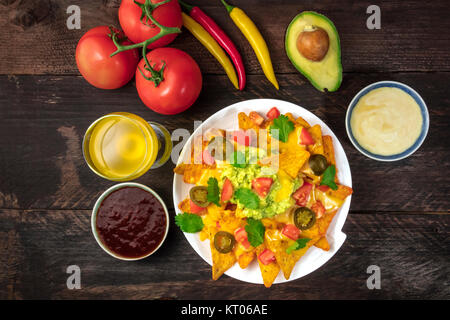 Una foto aerea di nachos con formaggio tradizionale spuntino messicano, con ingredienti come pomodoro, peperoncino, avocado, e il bianco e il rosso salse, Foto Stock