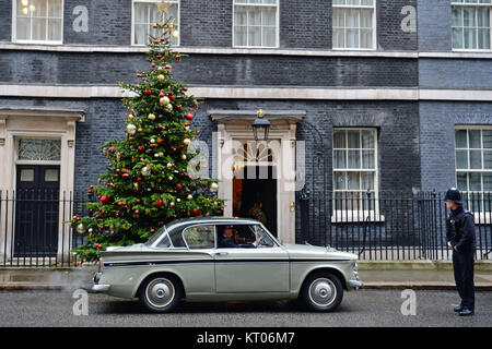 Un funzionario di polizia guarda Greg Knight MP in arrivo a Downing Street, Londra, in un 1961 Sunbeam Rapier auto. Foto Stock