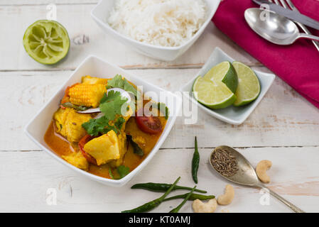 Il merluzzo bianco e il baby mais curry di cocco su un rustico tavolo bianco. Foto Stock