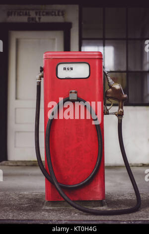 Un vecchio rosso della pompa a gas si trova al di fuori di una chiusura della stazione di rifornimento di carburante. Foto Stock