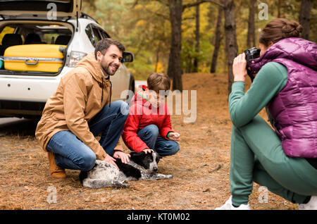 La famiglia felice giocando con il cane nella foresta Foto Stock