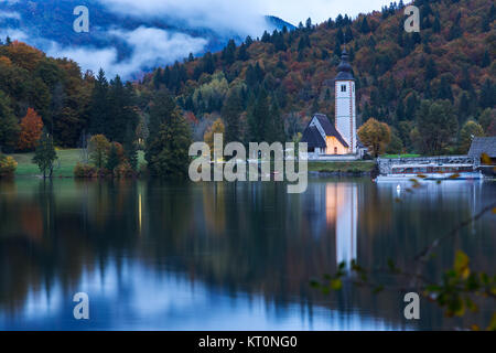 Il campanile della chiesa e il ponte di pietra sul lago di Bohinj Foto Stock