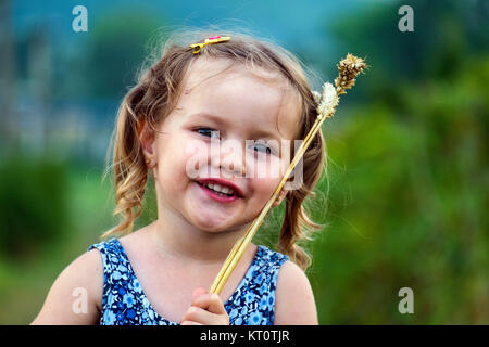 Bambina mettere il frumento spikelets sulla faccia Foto Stock