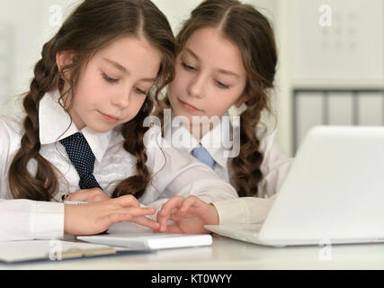 Gemelli ragazze utilizzando dispositivi digitali Foto Stock