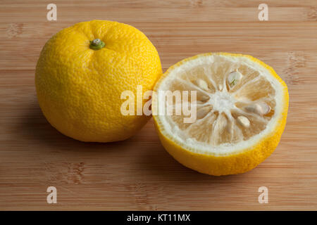 Giallo fresco intero e metà giapponese Yuzu frutto Foto Stock