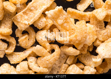 Deliziosa carne di maiale croccante crosta. Un nitido snack salato nero su sfondo lucido Foto Stock