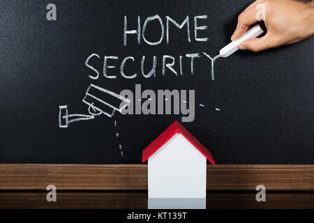 Modello di casa con la protezione della casa concetto sulla lavagna Foto Stock