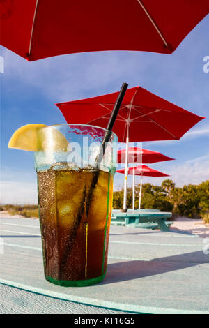 Bicchiere di ghiaccio freddo tè freddo al limone seduti sul tavolo sotto red ombrelloni a South Beach Bar & Grill sul Gasparilla Island Florida Foto Stock