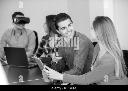 Team di persone motivate, utilizzando vari dispositivi ad una fusione di avvio. concetto, il lavoro di squadra Foto Stock