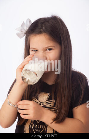 A sette anni di ragazza di bere un bicchiere di latte. Foto Stock