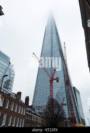 La Shard grattacielo con la sua parte superiore nel Cloud e un Rosso gru industriali in una fredda giornata invernale nel dicembre Londra Inghilterra Regno Unito Regno Unito Foto Stock