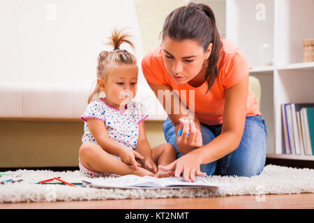 Madre e figlia nella loro casa. Essi sono in cerca di libro da colorare. Foto Stock