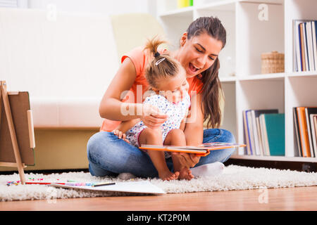 Madre e figlia nella loro casa. Essi sono in cerca di libro da colorare. Foto Stock