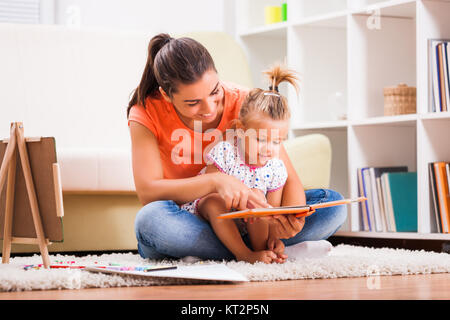 Madre e figlia nella loro casa. Essi sono in cerca di libro da colorare. Foto Stock