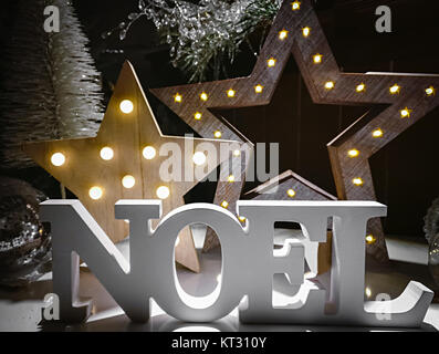 Noel parola fatta di lettere in legno su uno sfondo illuminato con stelle. Decorazione di natale. Foto Stock