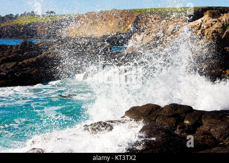 Forme d'onda colpendo costa rocciosa Foto Stock