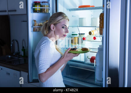 Donna sospette prendendo il cibo dal frigo Foto Stock