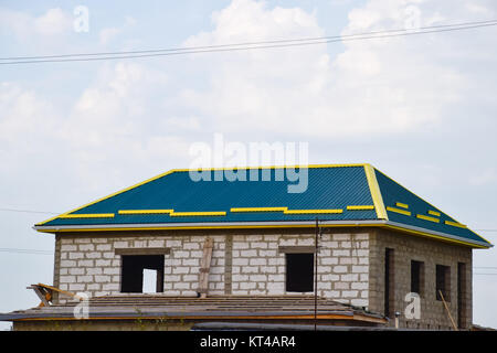 Una casa con un tetto in lastre di metallo. Pattinaggio giallo sul tetto Foto Stock