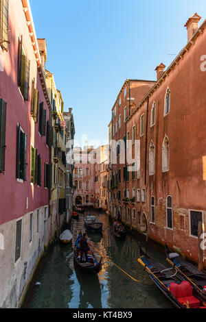 Facendo un giro sui tradizionali gondole a Venezia, Italia sul piccolo e stretto canale circondato con case Foto Stock