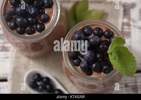 Sana colazione o spuntino mattutino con semi di chia budino di cioccolato e mirtilli. cibo vegetariano, la dieta e il concetto di salute Foto Stock