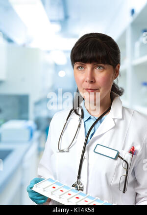 Medico donna, medtech o un medico scienziato in camice bianco con un vassoio di microscopici scorre in modo scientifico o laboratorio di analisi mediche Foto Stock