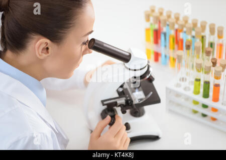 Giovane donna scienziato che lavora con microscopio in laboratorio Foto Stock