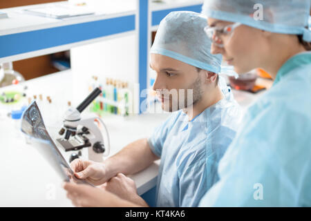 Vista laterale di chirurghi in medical uniformi analisi di immagine a raggi x in laboratorio Foto Stock