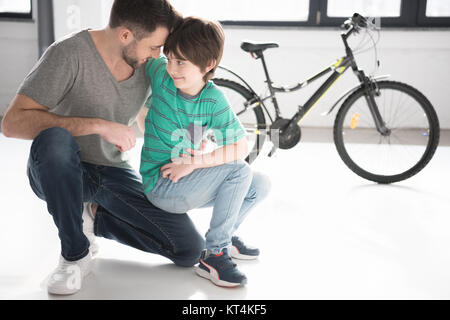 Felice padre e figlio abbraccia vicino nuova bicicletta nero Foto Stock