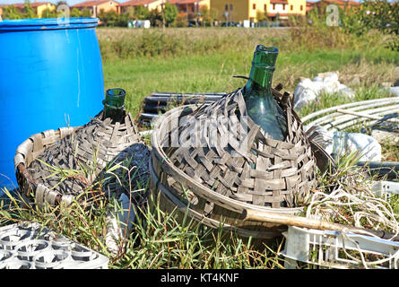 Vecchio vetro demijohn avvolto in vimini abbandonato Foto Stock